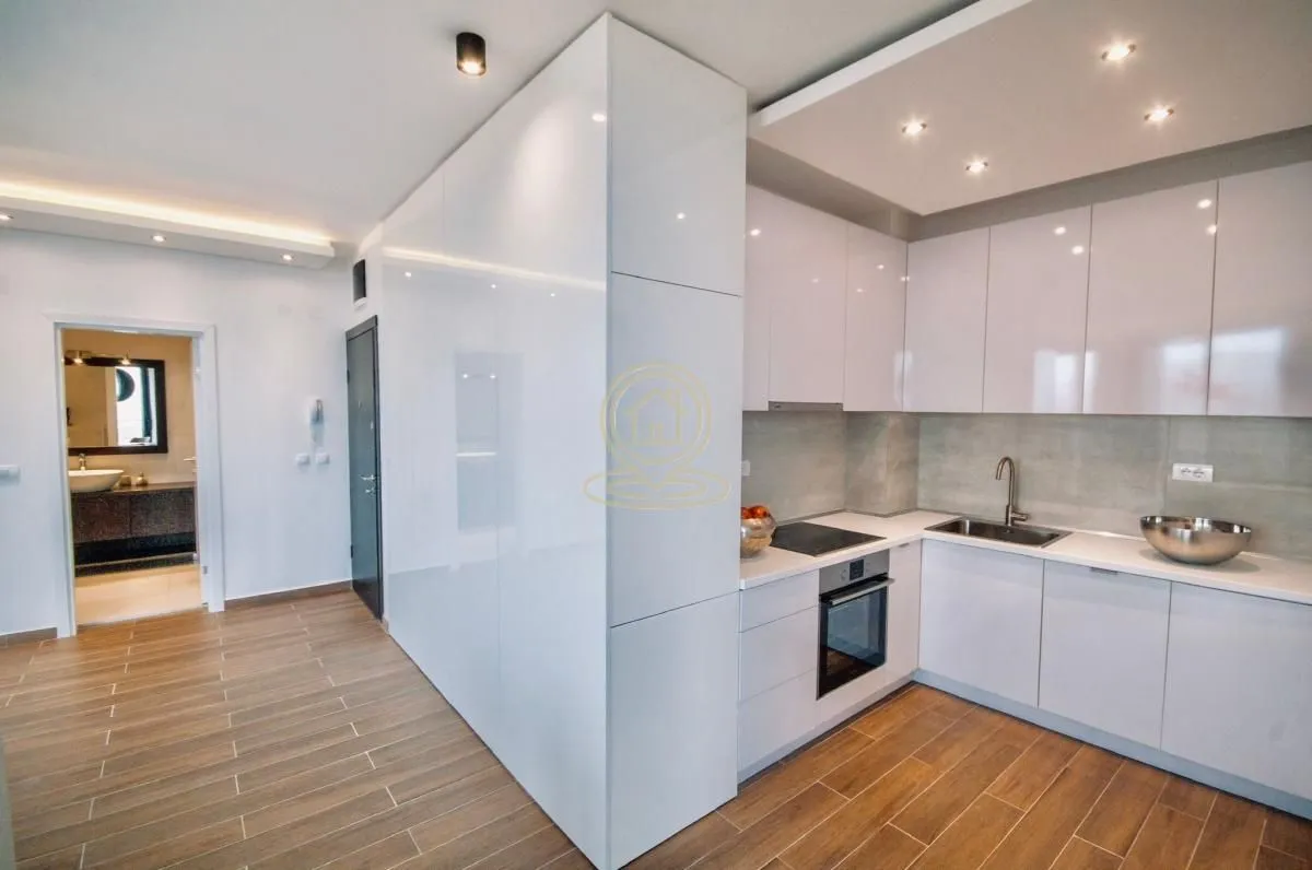 Modern white kitchen with built-in appliances and wooden flooring.