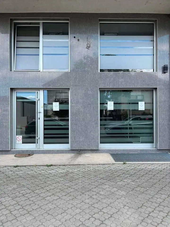 Exterior of a commercial space with a grey stone facade and large glass surfaces.