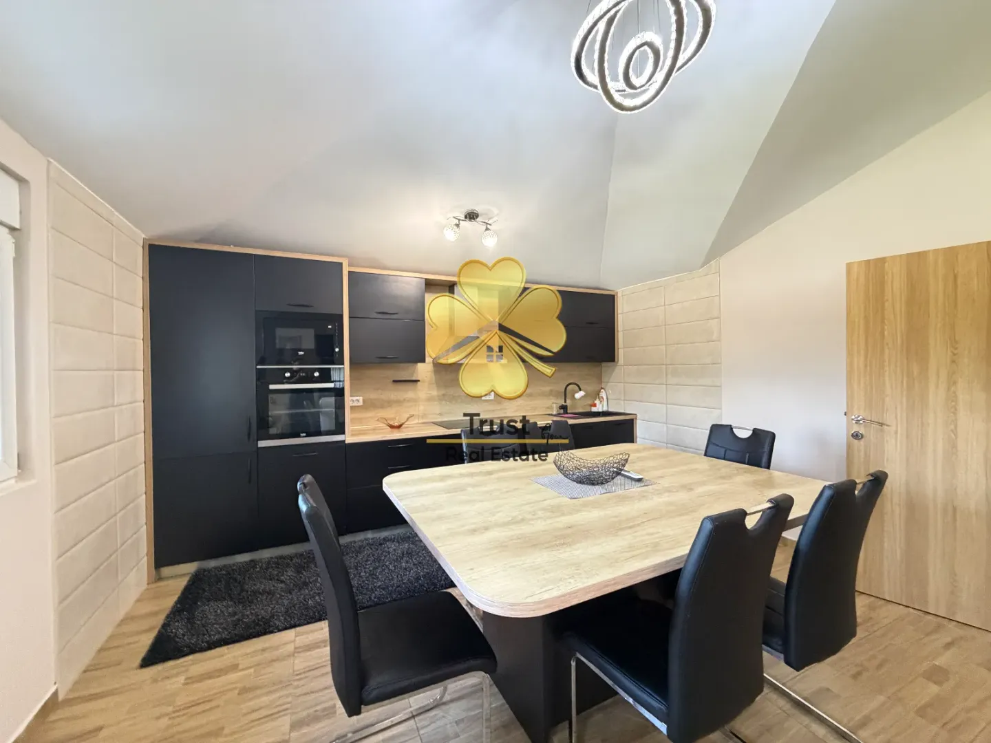 Modern kitchen with dining area and black cabinetry.