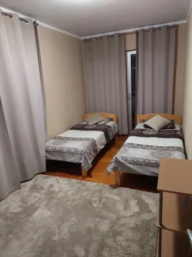 Bedroom with two wooden single beds, a rug, and curtains. - image 8