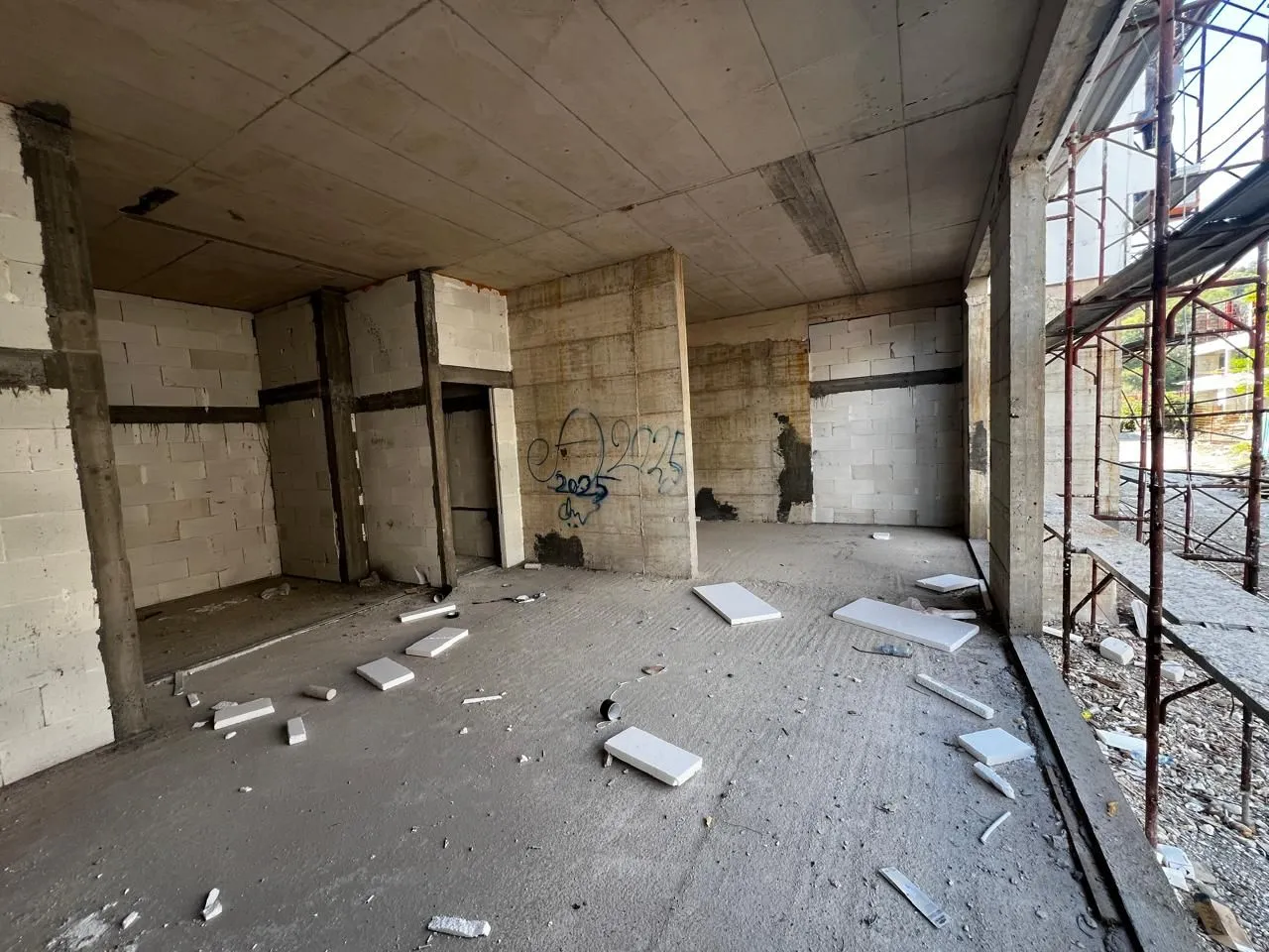 Unfinished interior of a building under construction with concrete pillars and block walls.