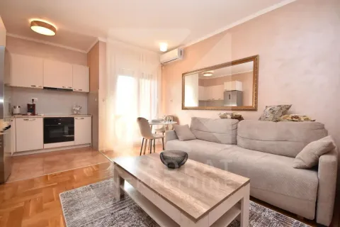 Living room with a sofa, coffee table and built-in kitchen in the background. - image 2