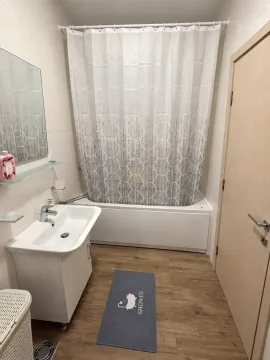 Bathroom with a bathtub, washbasin, and mirror. - image 11
