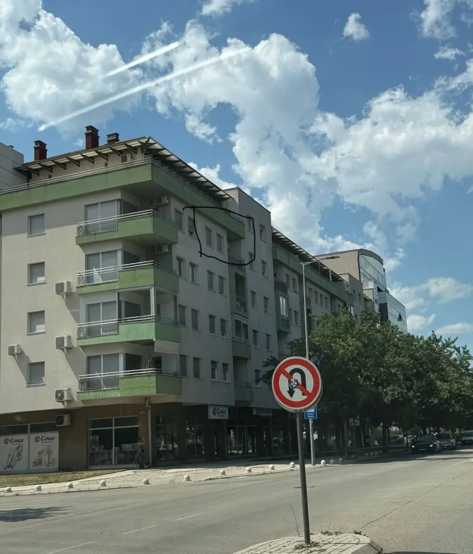 Pogled sa ulice na višespratnu stambenu zgradu sa balkonima.