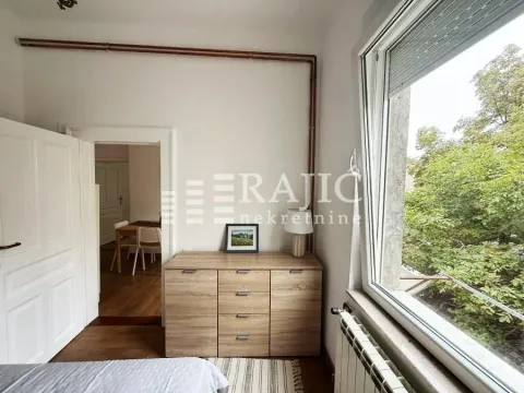 Bedroom with a chest of drawers and a view of greenery through the window. - image 9