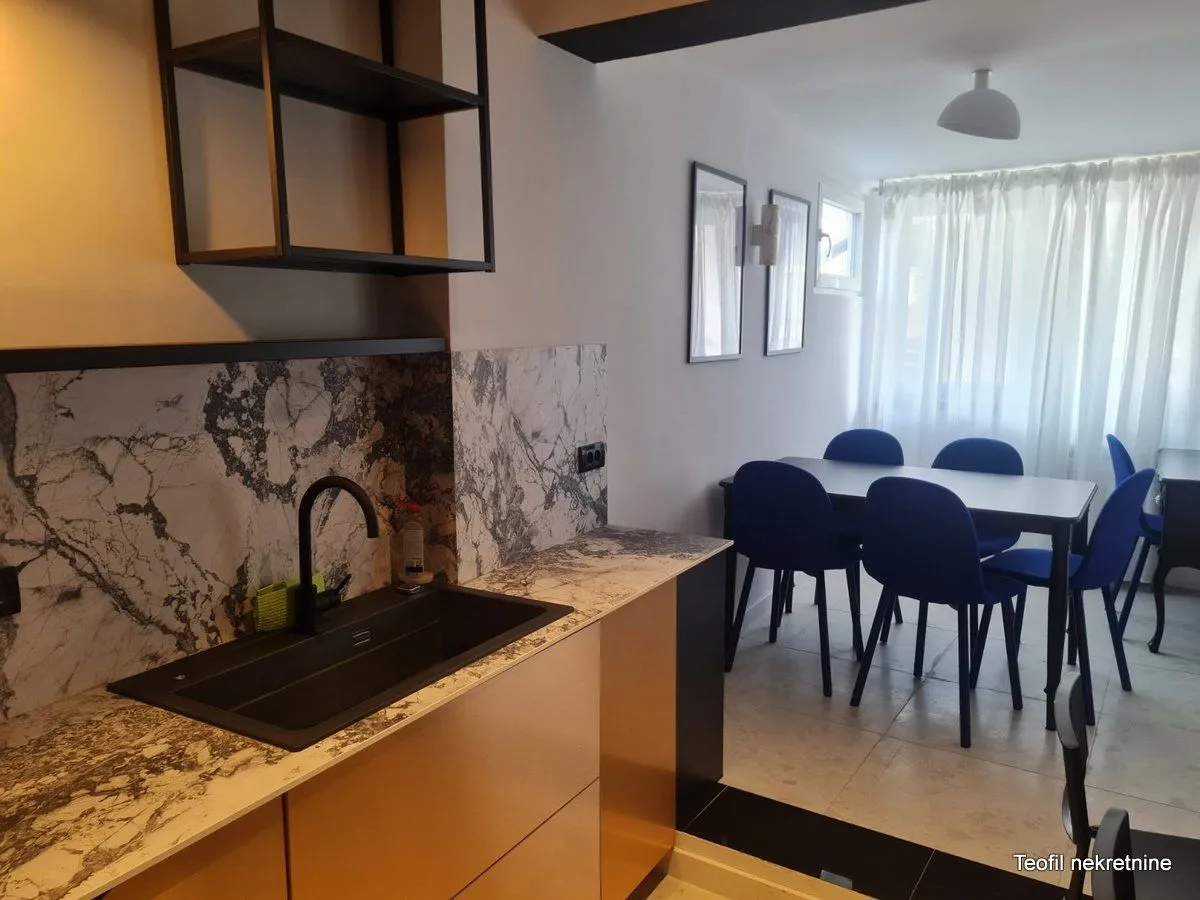 Kitchen with a sink and an open dining area with blue chairs.