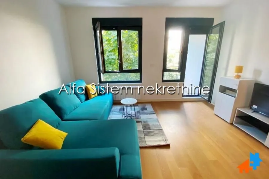 Living room with a green corner sofa and a view of greenery.