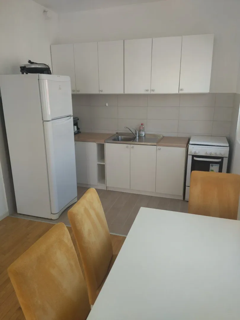 Small white kitchen with a refrigerator and a dining table.