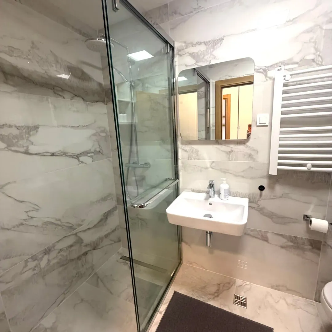 Modern bathroom with a walk-in shower and washbasin, finished with marble tiles.