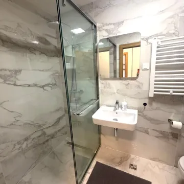 Modern bathroom with a walk-in shower and washbasin, finished with marble tiles. - image 7