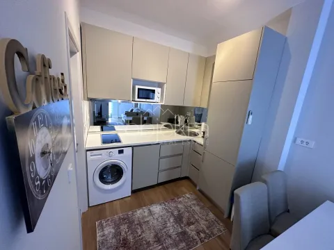 Small kitchen with light cabinetry, sink, built-in cooktop, and washing machine. - image 9