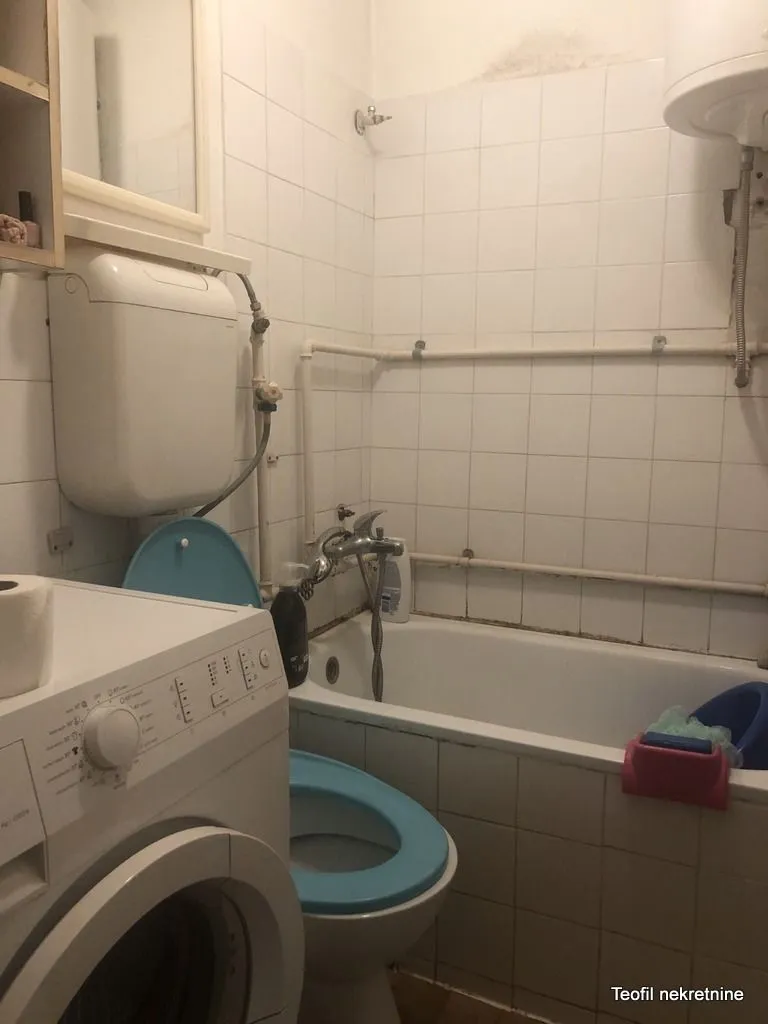 Manje opremljeno kupatilo sa kadom, toaletom i veš mašinom.