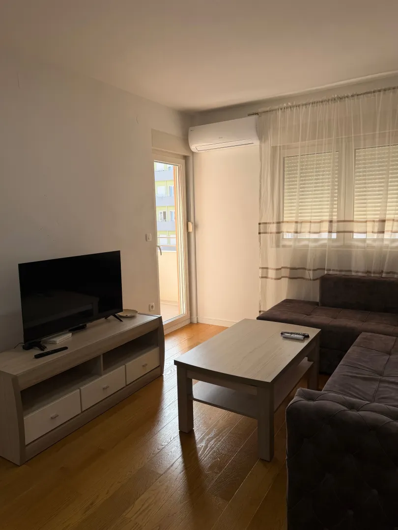 Living room with a sofa, TV stand, and balcony access.