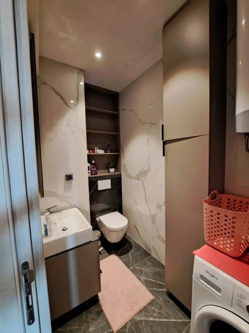 Moderne kupatilo sa umivaonikom, toaletom, tušem i ugrađenim ormarićem.