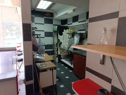 Restaurant kitchen with work surfaces, refrigerator, and shelving. - image 6