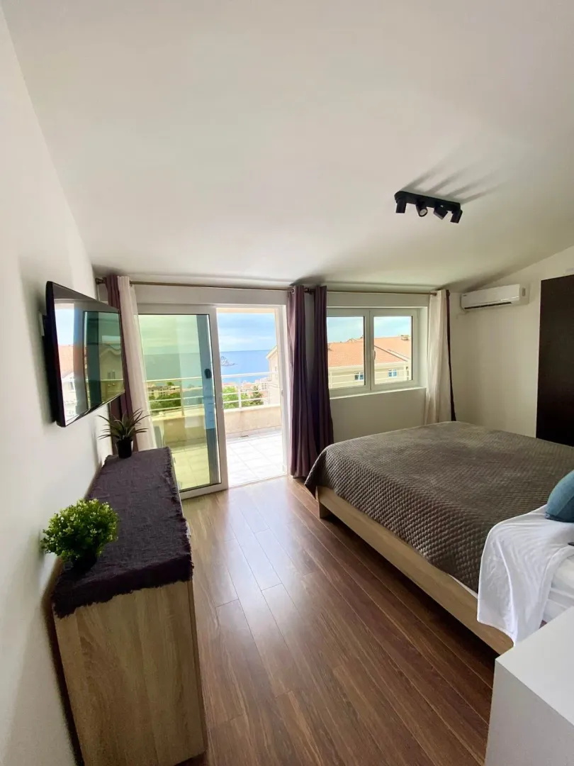 Furnished bedroom with a double bed and access to a terrace with a sea view.