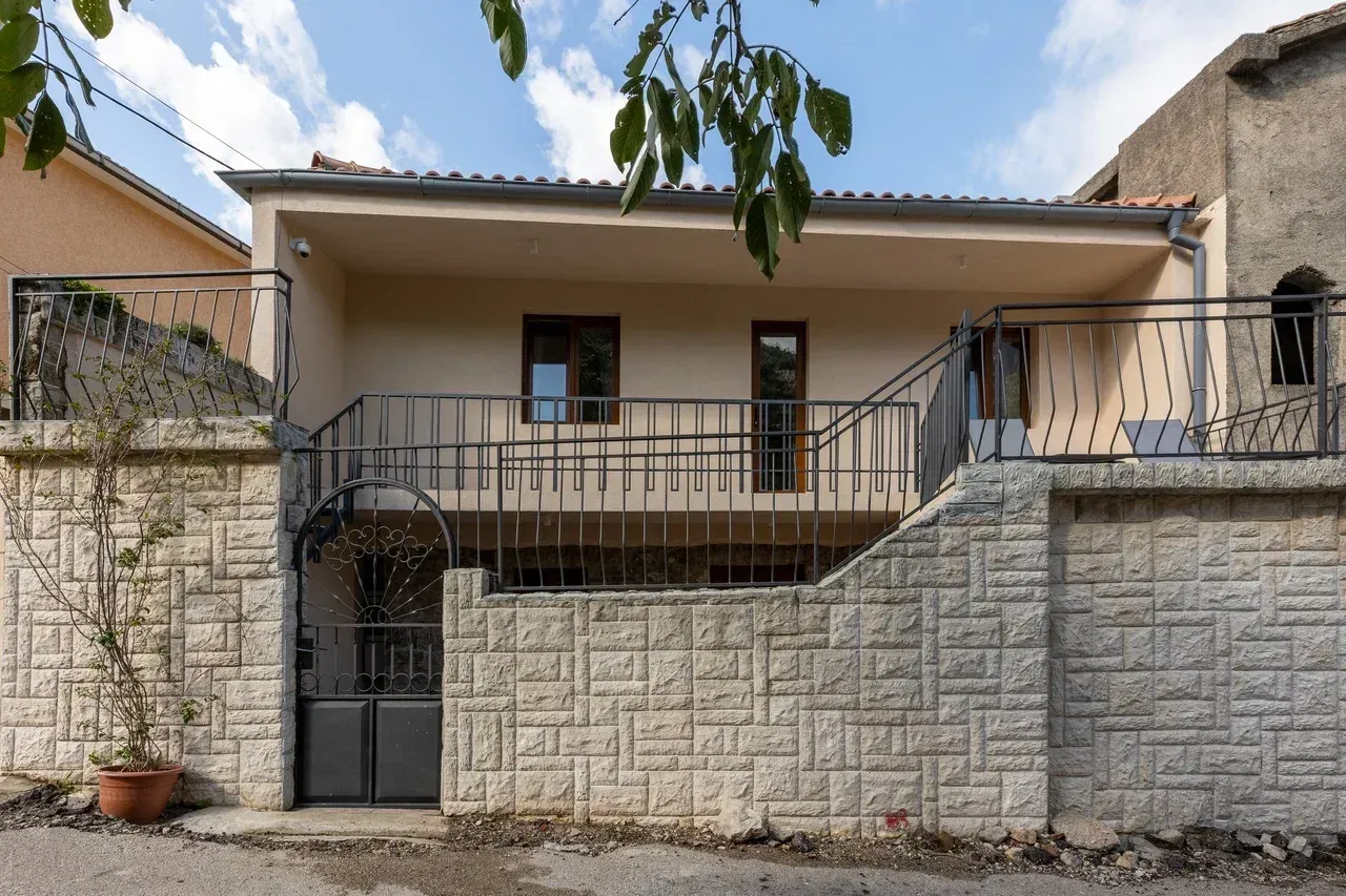 Eksterijer kuće sa dvorištem, ogradom i terasom.