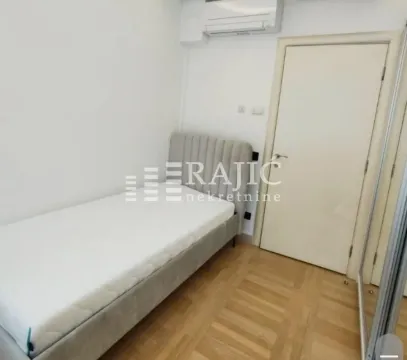 Manja spavaća soba sa krevetom i parketom na podu. - image 9