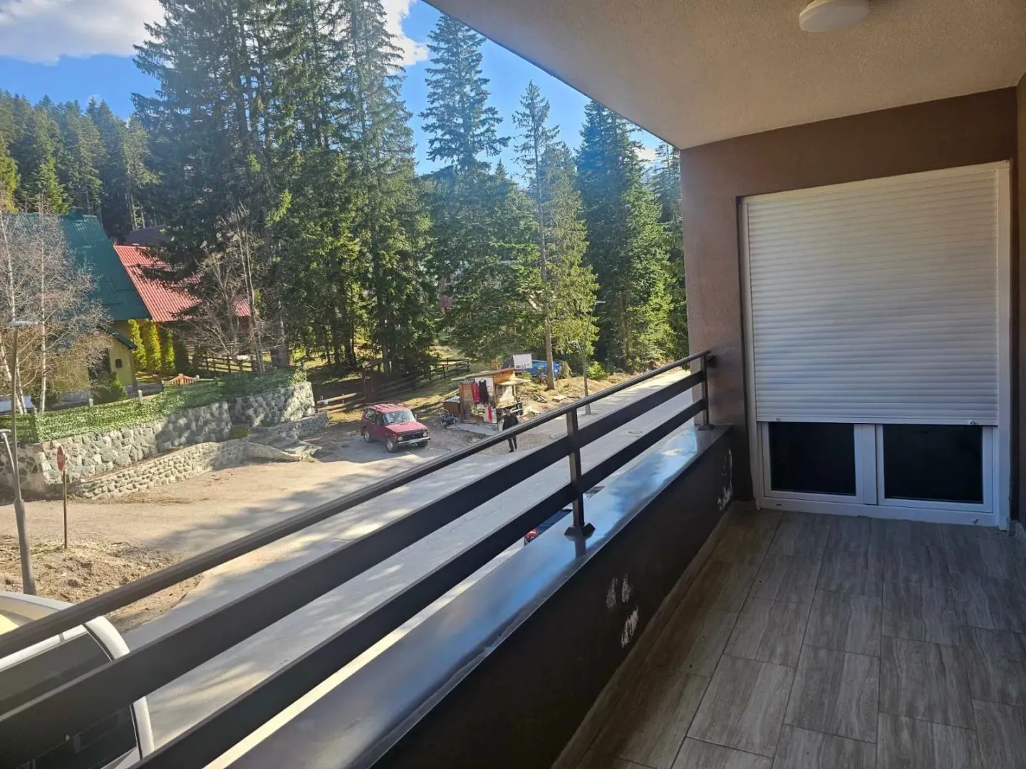 Natkriveni balkon sa pogledom na ulicu i okolno zelenilo.