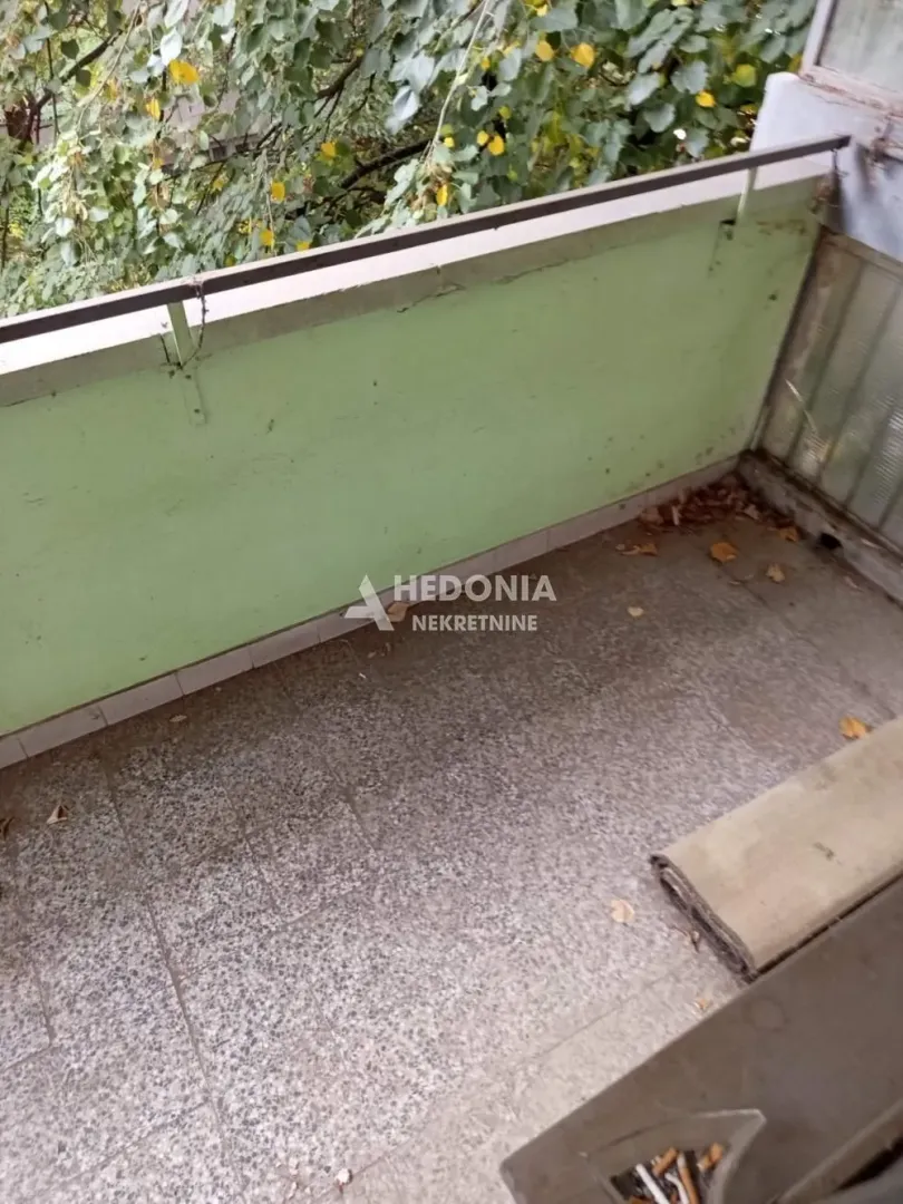 Manji balkon sa pogledom na drveće.