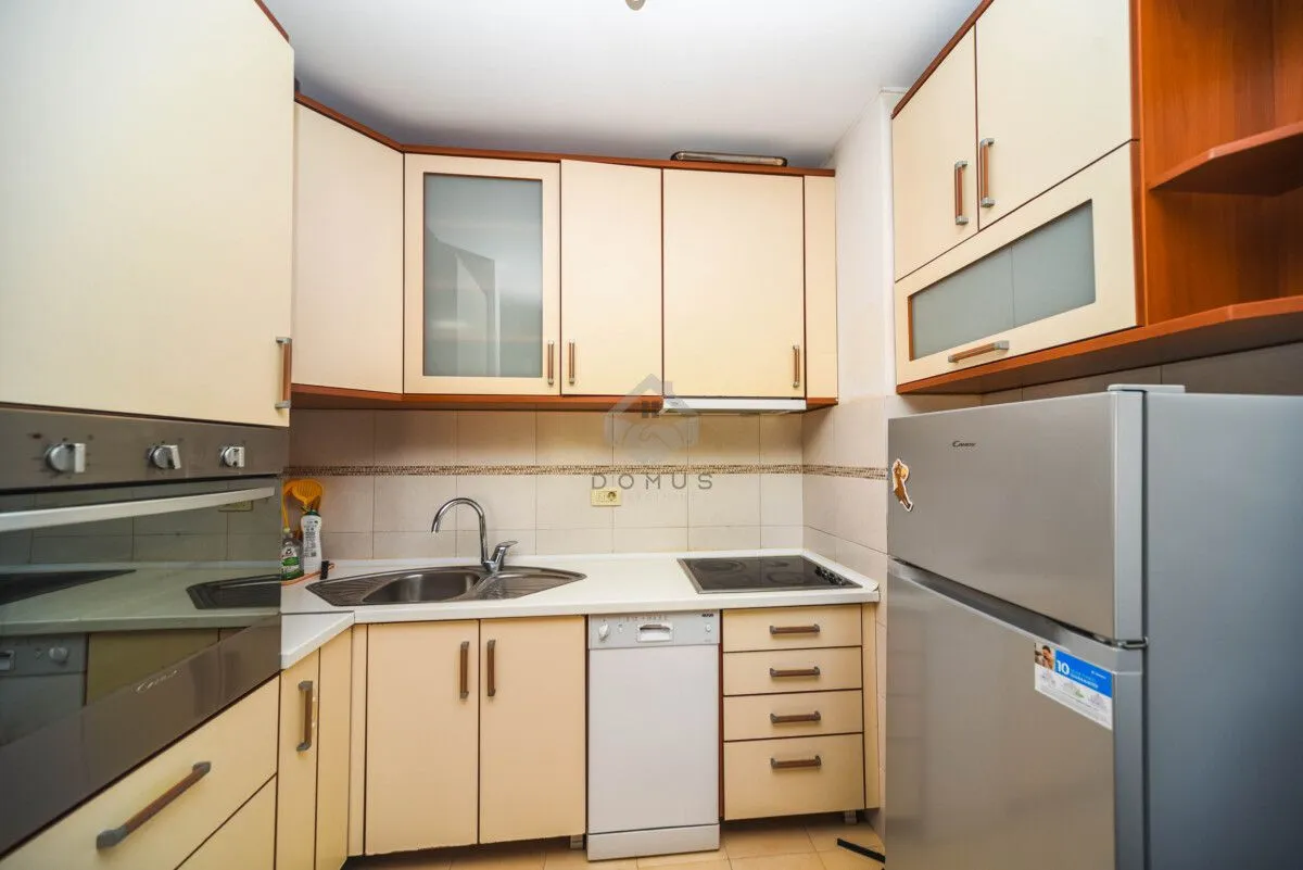 The kitchen is equipped with light cabinetry, a built-in oven, a sink, and a refrigerator.
