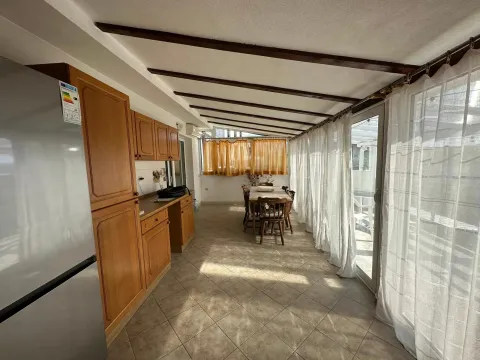 Spacious kitchen with wooden cabinetry and a dining area. - image 8