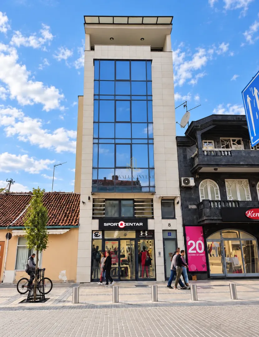 Exterior view of a modern commercial and residential building with a ground floor shop.