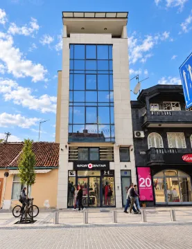 Exterior view of a modern commercial and residential building with a ground floor shop. - image 2