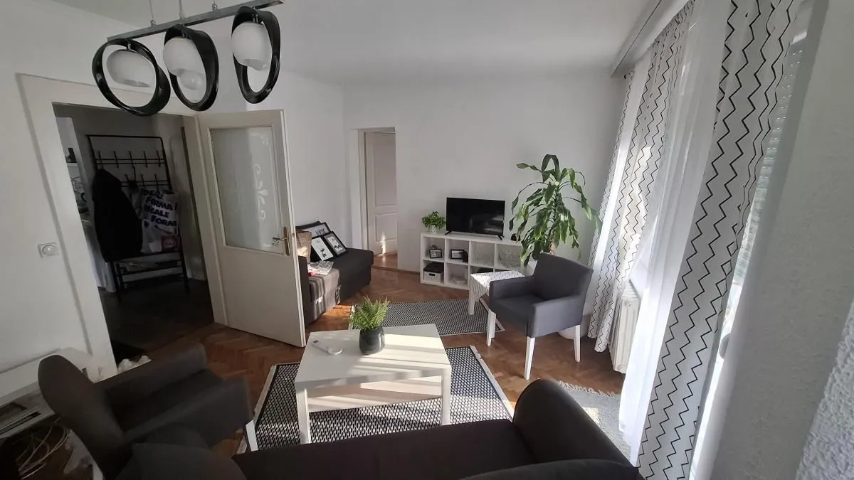 Dnevna soba sa garniturom, stočićem i televizorom.