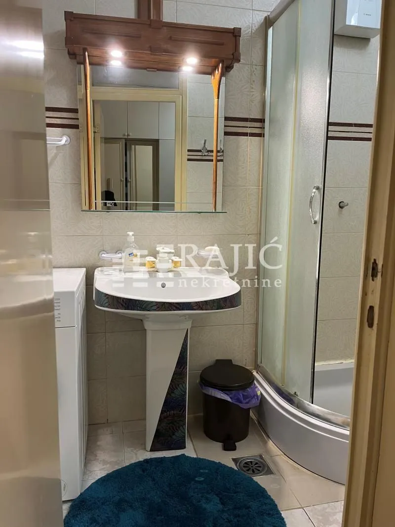 Smaller bathroom with a washbasin, mirror and shower cabin.