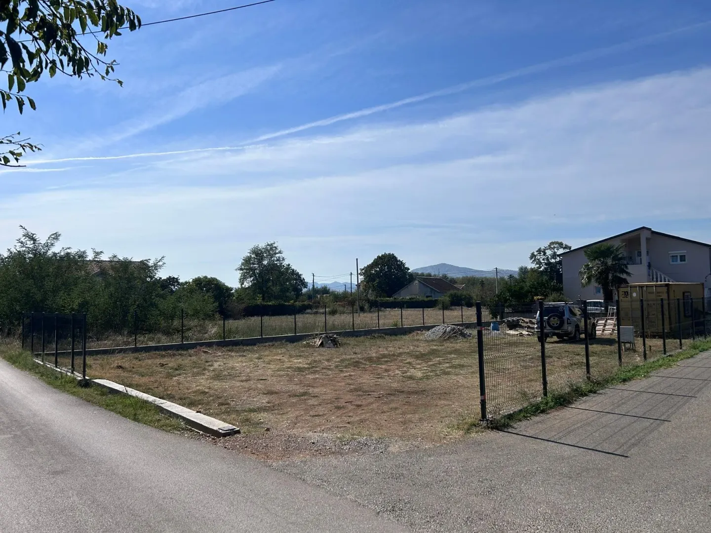 Pogled na ograđeni građevinski plac pored puta.