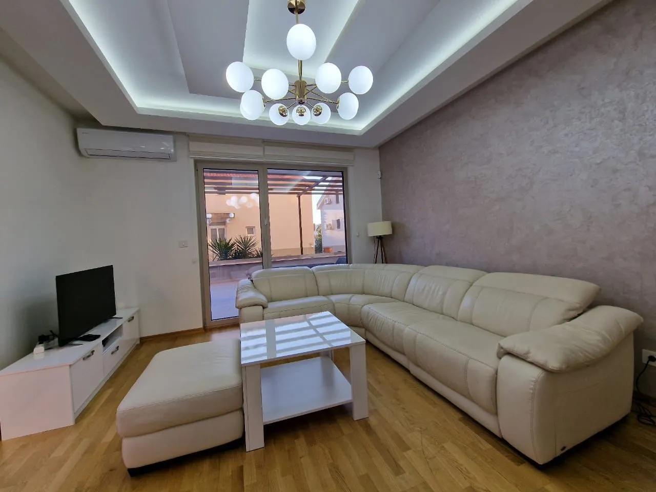 Living room with a large white sectional sofa, coffee table, and TV unit.