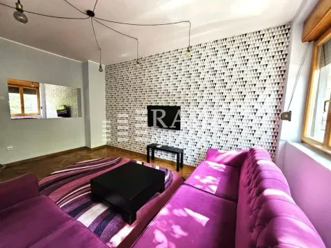 Living room with a purple sofa and decorative wallpaper on the wall. - image 2