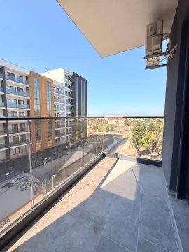 Modern and spacious balcony with a glass railing and a view of surrounding buildings and landscape. - image 9