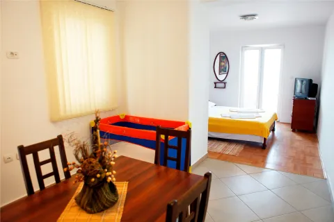 Living room with a dining table and a view into the bedroom. - image 5