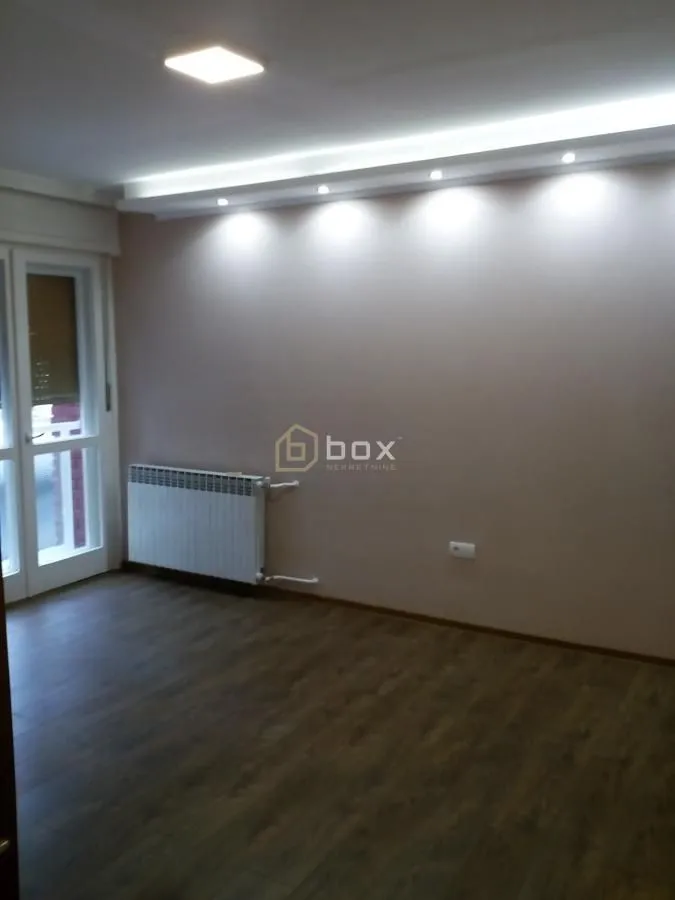Empty room with parquet flooring, a radiator, and a drop ceiling with recessed lighting.