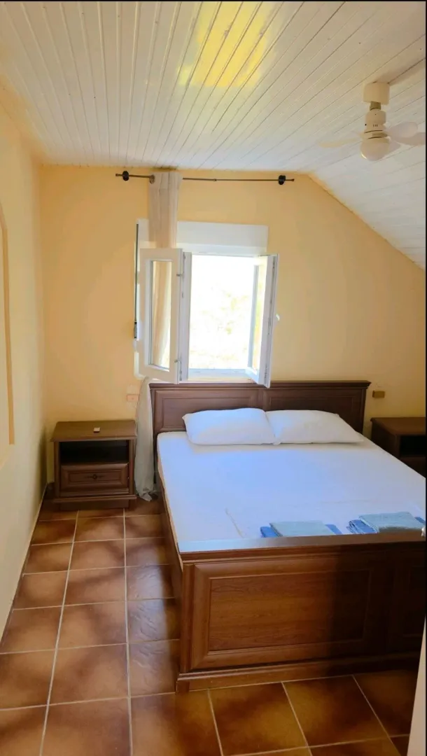A bedroom with a double bed, wooden furniture, and tiled flooring.
