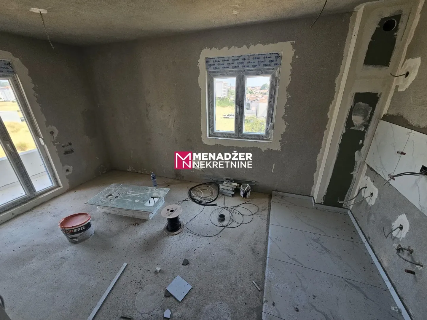 Unfinished room in an apartment under construction with installed windows.