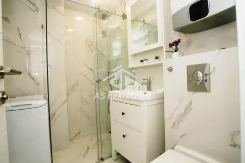 Modern bathroom with a shower cabin, washbasin, and washing machine. - image 21