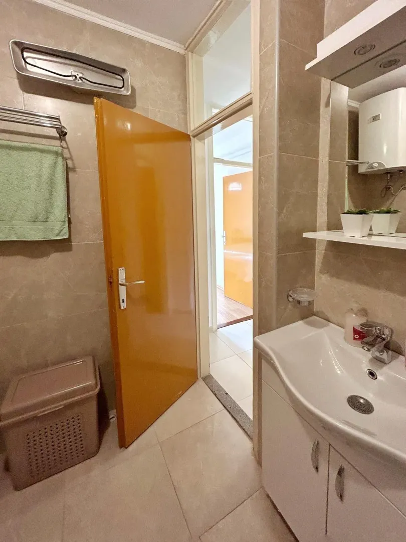 Jednostavno kupatilo sa umivaonikom, pločicama toplih tonova i žutim vratima.