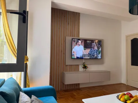 Dnevna soba sa garniturom, TV-om i drvenim zidnim panelom. - image 7