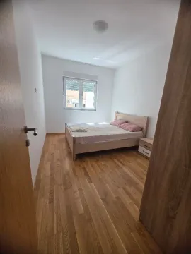 Spavaća soba sa bračnim krevetom, drvenim podom i prozorom. - image 6