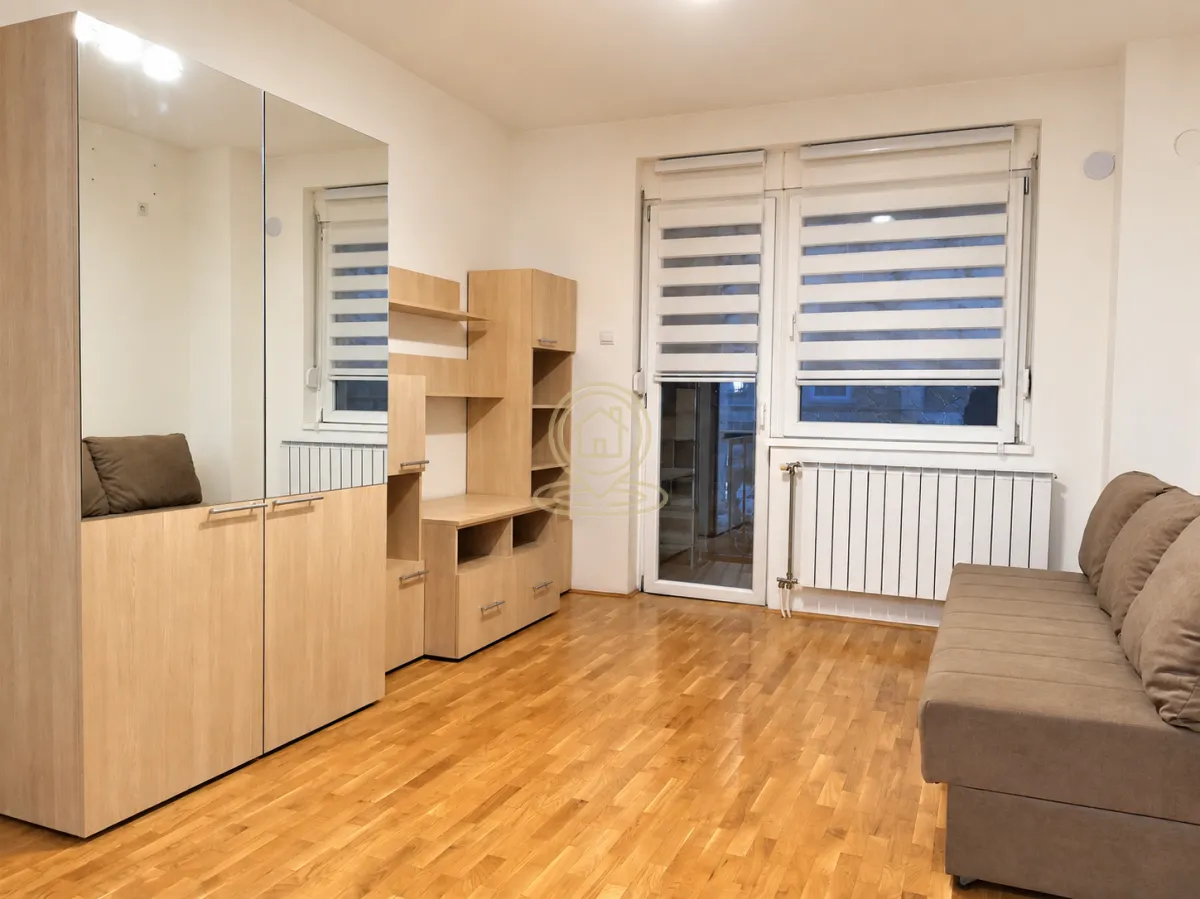 Living room with a sofa, a large mirrored wardrobe, and wooden furniture.