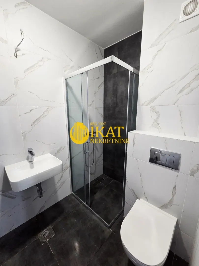 Modernly equipped bathroom with a shower cabin, washbasin, and toilet.
