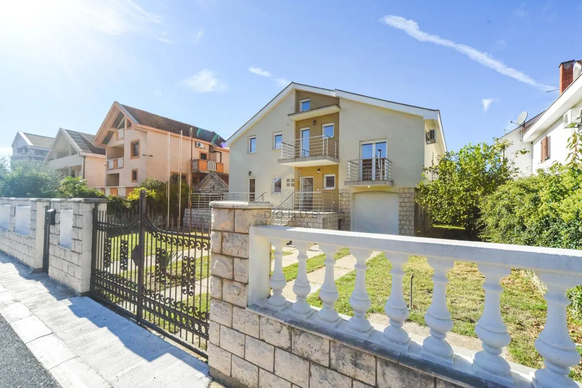 Exterior view of the house with a courtyard and fence.