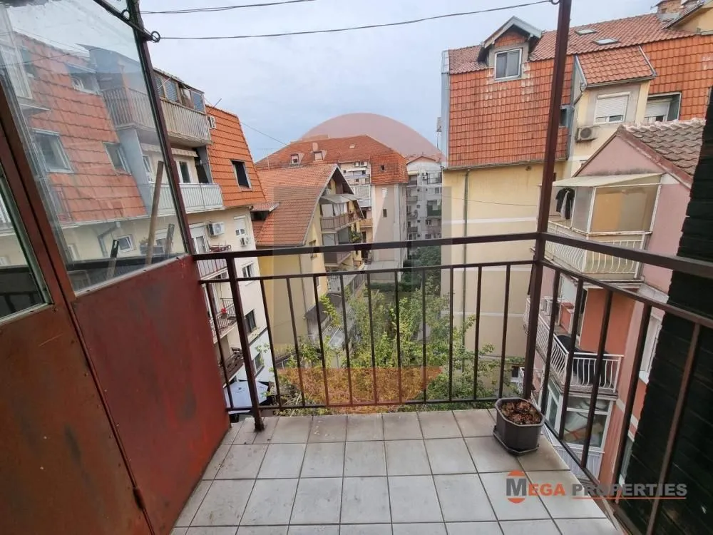 Manji popločani balkon sa metalnom ogradom i pogledom na okolne zgrade.