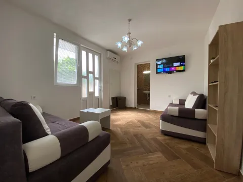 Living room with a sofa set, TV, and a view of the bathroom in the background. - image 2