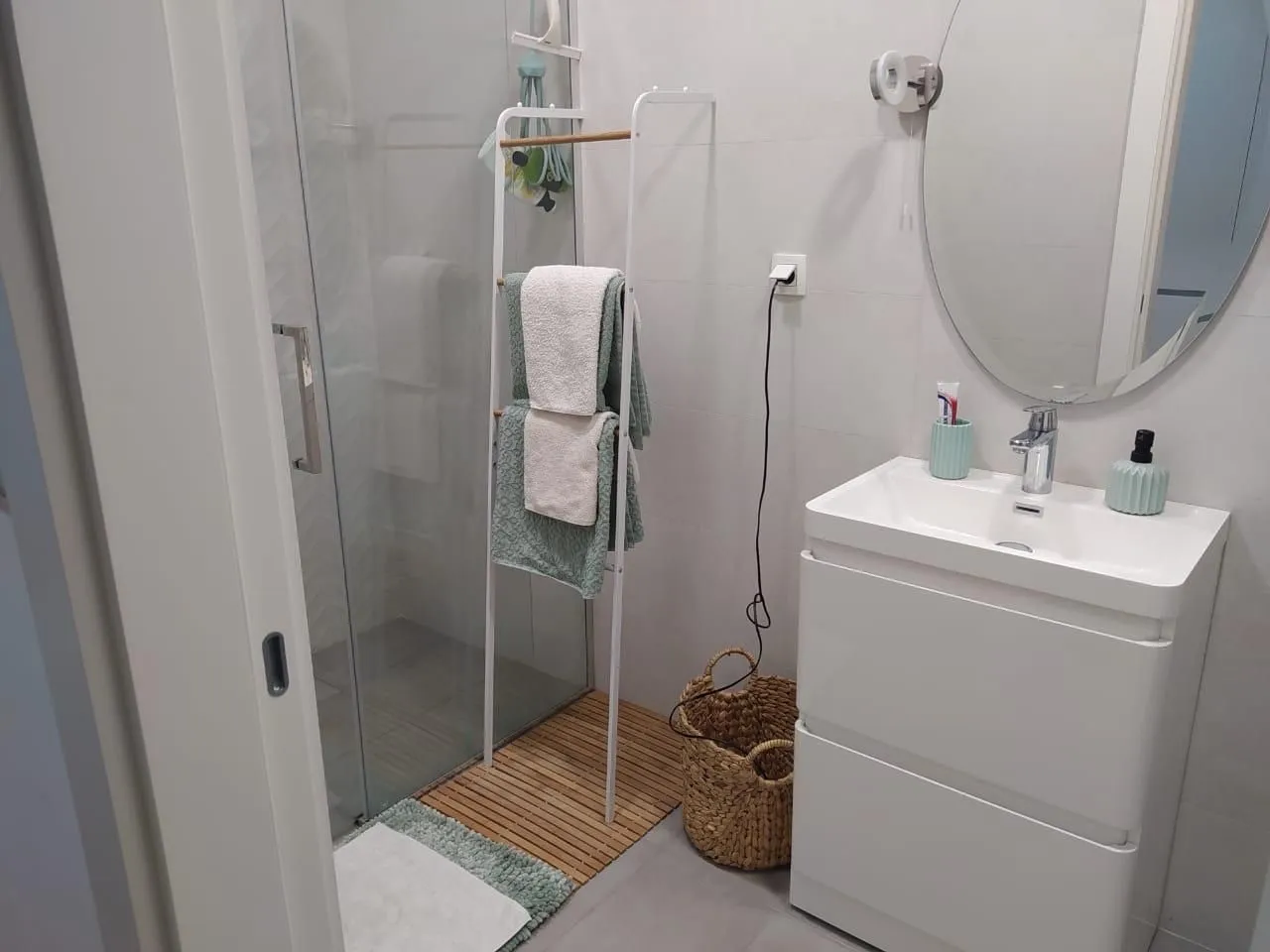 Modernly equipped bathroom with a walk-in shower, washbasin, and mirror.