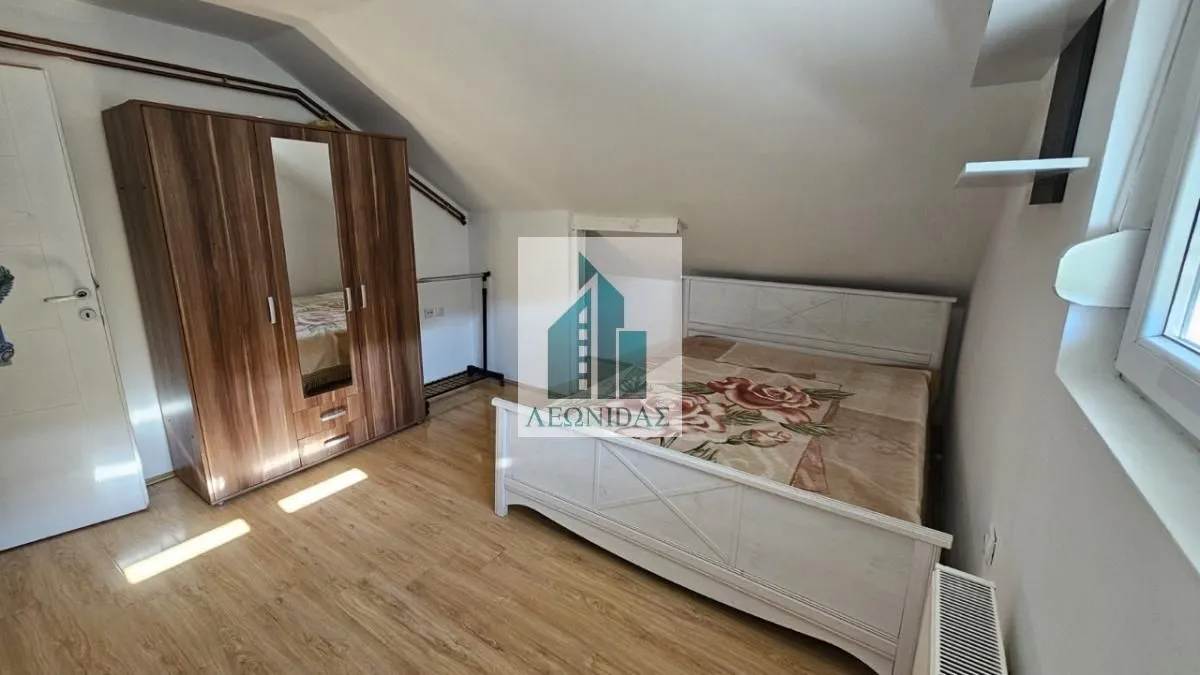 Attic bedroom with a double bed and a wooden wardrobe.