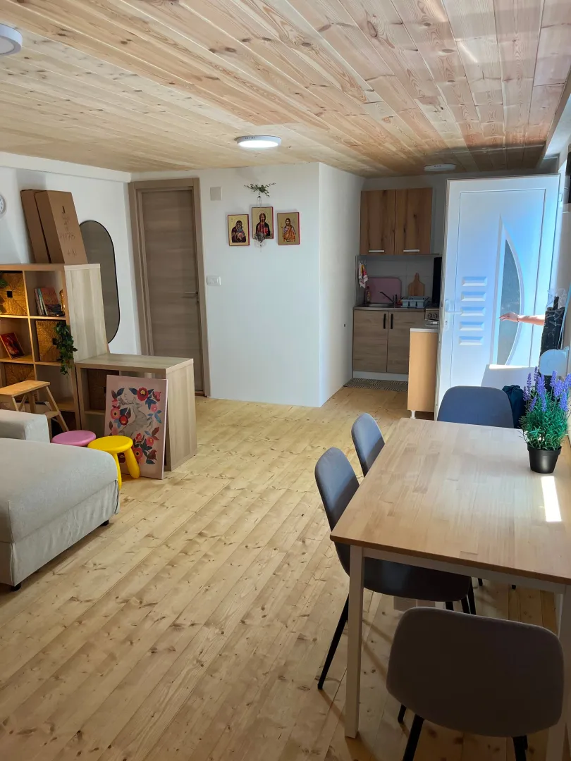 Dnevni boravak sa trpezarijom, drvenim plafonom i ulaznim vratima.